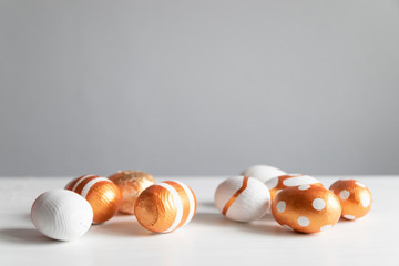 Golden eggs on a white table with a copyscape. Holiday composition banner.