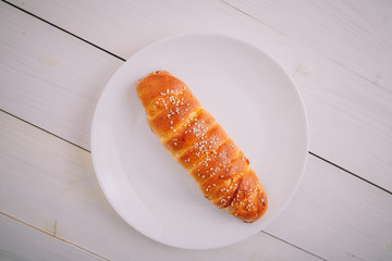 Roll-up plum pie on white plate on wooden background. Tasty healthy food. Diet, nutrition, eating habits concept. Place for text