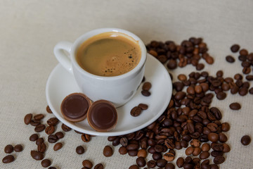 A cup of strong coffee. Coffee in a white cup on a saucer. Coffee beans.