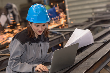Confident female engineer checks her laptop in the factory