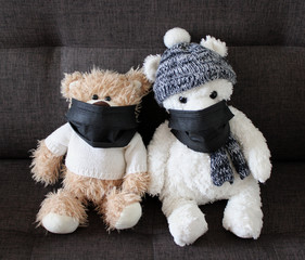 Soft toys bears in a black medical masks sit on a black sofa. Schools and kindergartens are under quarantine. Home schooling. 
