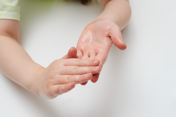 Child rubbing antibacterial gel on hands isolated white