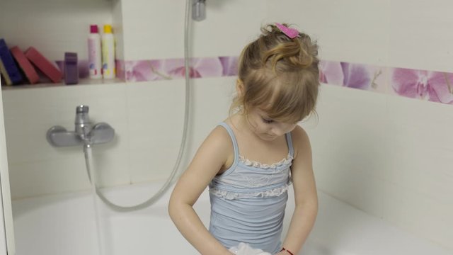 Cute blonde girl takes a bath in swimwear. Little child, 4 years old. Hygiene