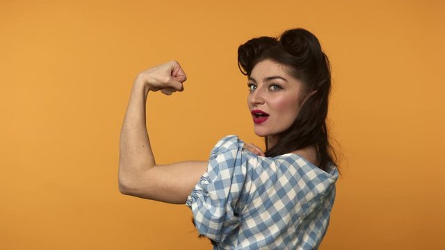 Confident pin up woman showing biceps and winking with smile