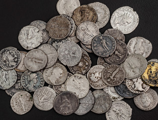 Antique Roman coins, a small pile of cash on a black background