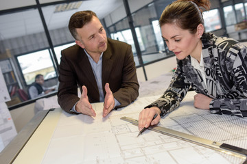 Serious manager is telling female architectural assitant off