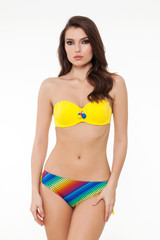 Obraz premium beautiful girl posing in stylish flower patterned chic colorful and yellow bikini on white background.