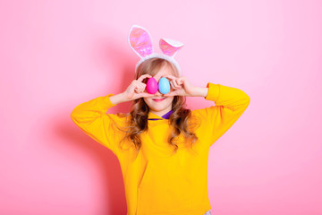 Funny girl kid blonde with Bunny ears holds bright Easter eggs. Happy Easter! Traditions, holidays, spring, religion concept.