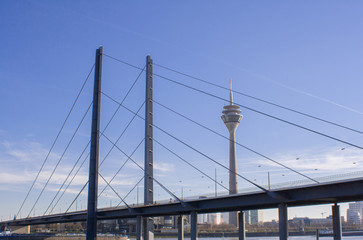 Düsseldorfer Fernsehturm, eines der Wahrzeichen der Stadt. Im Vordergrund Ausschnitte der beliebten Rheinkniebrücke in NRW.