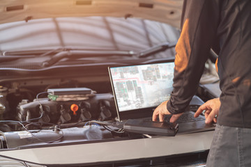 Professional mechanic man using laptop computer to solve troubleshooting problem of the car