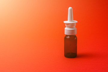 nasal spray in dark bottle with nozzle on red background.