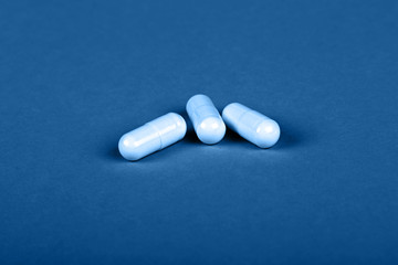 Close up three gel cap pills over blue background