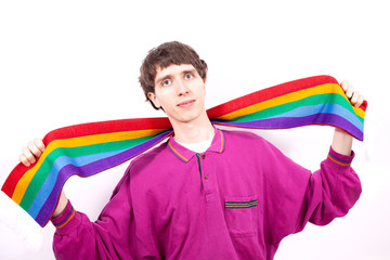A young man in a pink sweatshirt holds a rainbow scarf which is a symbol of peace and LGBT people. He looks with hope and kindness.