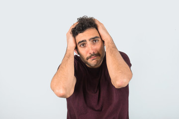 Young man with a mustache with expression of tiredness and sadness and hands on his head. Purple...