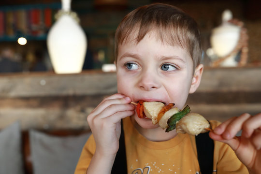 Boy eating meat and vegetable kebab