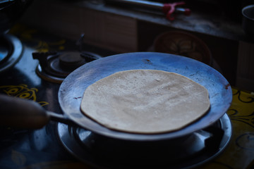 woman cooking a Indian chapati in a pan  