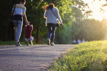Obraz premium Happy family - mom, dad and kid - on a walk in the park in summer.