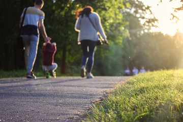 Happy family - mom, dad and kid - on a walk in the park in summer.