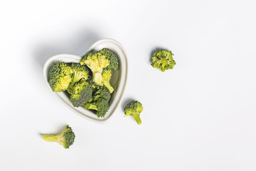 Fresh broccoli in a heart shaped bowl on white background