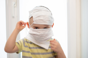 Toddler boy in wearing many medicine masks, quarantine at home, virus protection