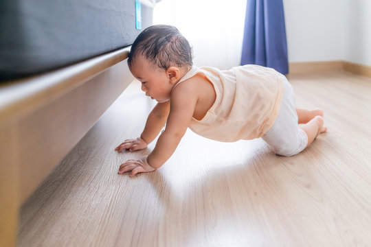 Curious little baby was crawling, bumping his head against the edge of the bed,At an age requires care and attention at all times.