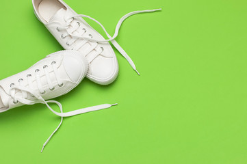 White female fashion sneakers on green background. Flat lay top view copy space. Women's shoes. Stylish white sneakers. Fashion blog or magazine concept. Minimalistic shoe background, sport shoes