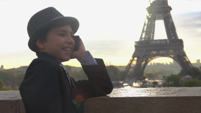 Handsome teenage boy in a hat is talking on the phone on the background of the Eiffel tower, Paris, France