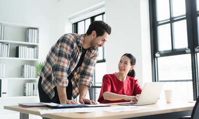 Happy and relaxed office workers discuss new project or work plan document casually on the office desk, the concept of teamwork, working lifestyle, positive healthy working, creative meeting teamwork