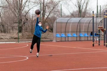 Obraz premium A young woman is playing sports on a sports field in a mask. Protection from coronavirus infection with a medical mask.