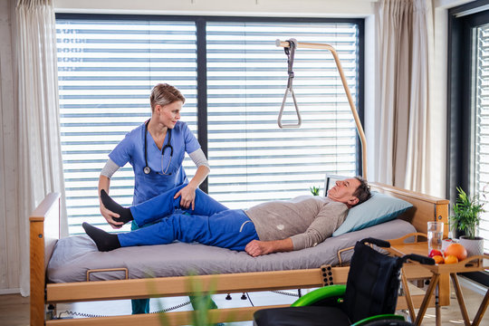 A healthcare worker and senior patient in hospital, physiotherapy.