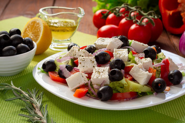 Obraz na płótnie Canvas Greek salad with fresh cucumber , tomatoes, sweet pepper, lettuce, red onion, feta cheese and olives with olive oil. Healthy diet