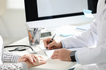 Doctor working with patient at desk in office, closeup