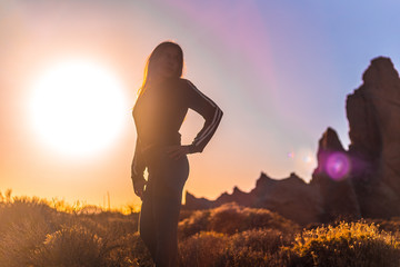 Lifestyle, silhouette of a young brunette in an orange sunset on the Teide volcano looking to the right. Tenerife