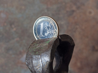 one Euro coin clamped in a pincer. Concept of financial problems , crisis, and economic downturn in Europe