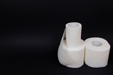 Three rolls of toilet paper on black background.