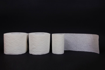 Three rolls of toilet paper on black background.