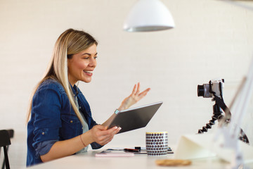 Young business woman recording video for her vlog and holding digital tablet