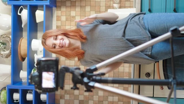 Vertical shoot: Food blogger girl influencer is recording a video or podcast in the kitchen. Makes lifestyle blog vlog about healthy and unhealthy foods. A woman communicates with subscribers.