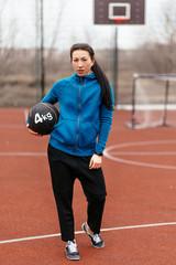 A young woman is engaged in sports on the Playground. Exercises with the medicine balls on the outdoor.