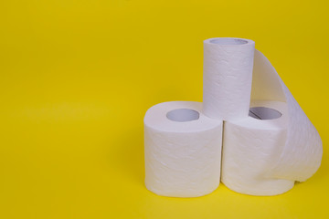 Three rolls of toilet paper on yellow background