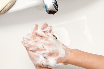 a Washing hands with soap under the faucet with water