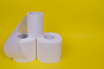Three rolls of toilet paper on yellow background