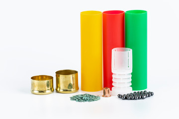 Components for the manufacture of a hunting cartridge. Housings, gunpowder, injection capsules, block and lead pellet, on white background.