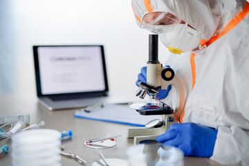 Doctor with microscope analyzing blood samples, coronavirus concept.