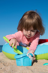little cute girl sits in a children's pool on the beach