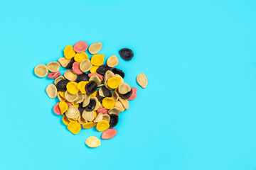 Colorful uncooked italian pasta Orecchiette on bright blue background