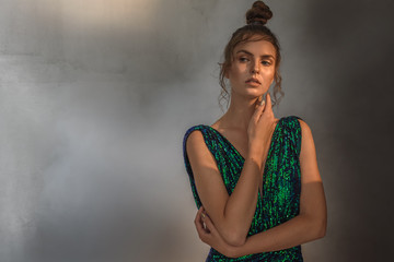 portrait of a young, pretty girl, in a green dress in a gray light room, which is conceived and...