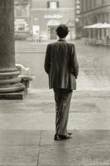 Rear view of man in suit waiting by column during rainy season