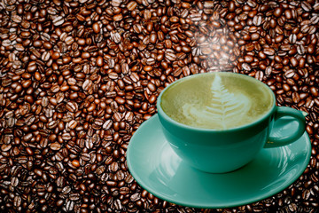 Coffee cup with latte art with smoke on fresh roasted coffee beans background