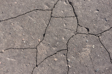 Cracks in grey concrete surface. Old destroyed asphalt with cracks. Asphalt in cracks texture.